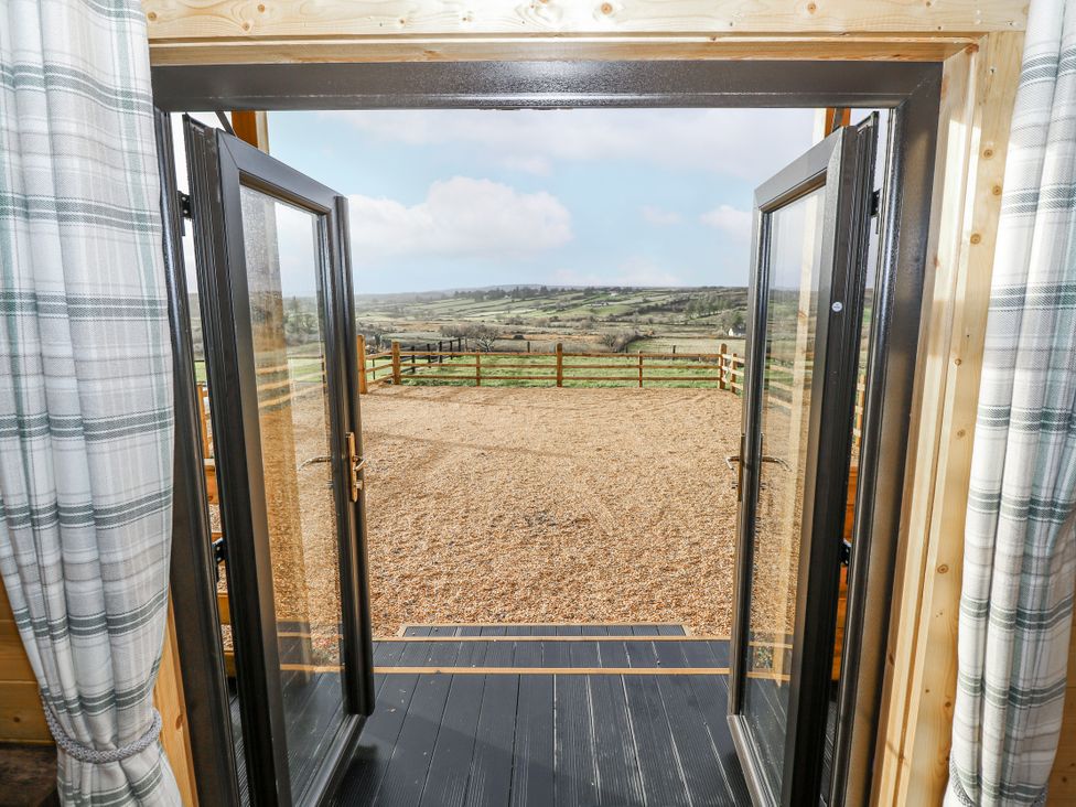 Double doors leading to a gravel area with a fenced landscape at Glenview Log Cabin in Ballycastle