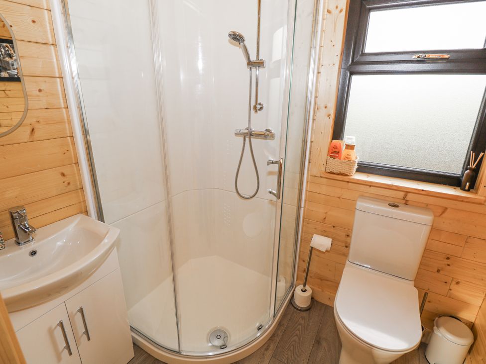 A bathroom with a shower, sink, and toilet at Glenview Log Cabin in Ballycastle