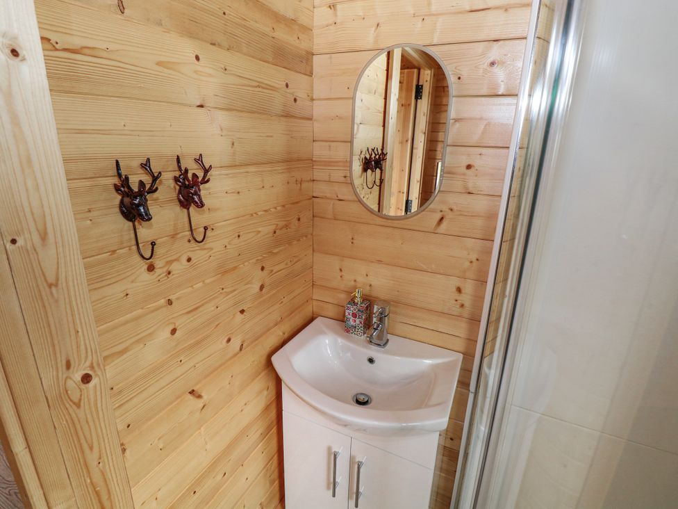 A bathroom with a sink and mirror at Glenview Log Cabin Ballycastle