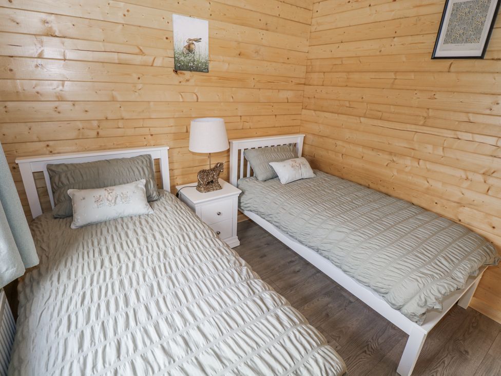 A bedroom with two beds and a nightstand at Glenview Log Cabin in Ballycastle