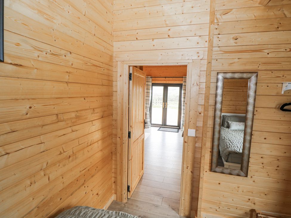 A bedroom entrance with wooden walls and a doorway at Glenview Log Cabin Ballycastle