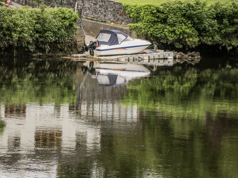 A boat moored by a dock reflecting on water at Glenview Log Cabin Ballycastle