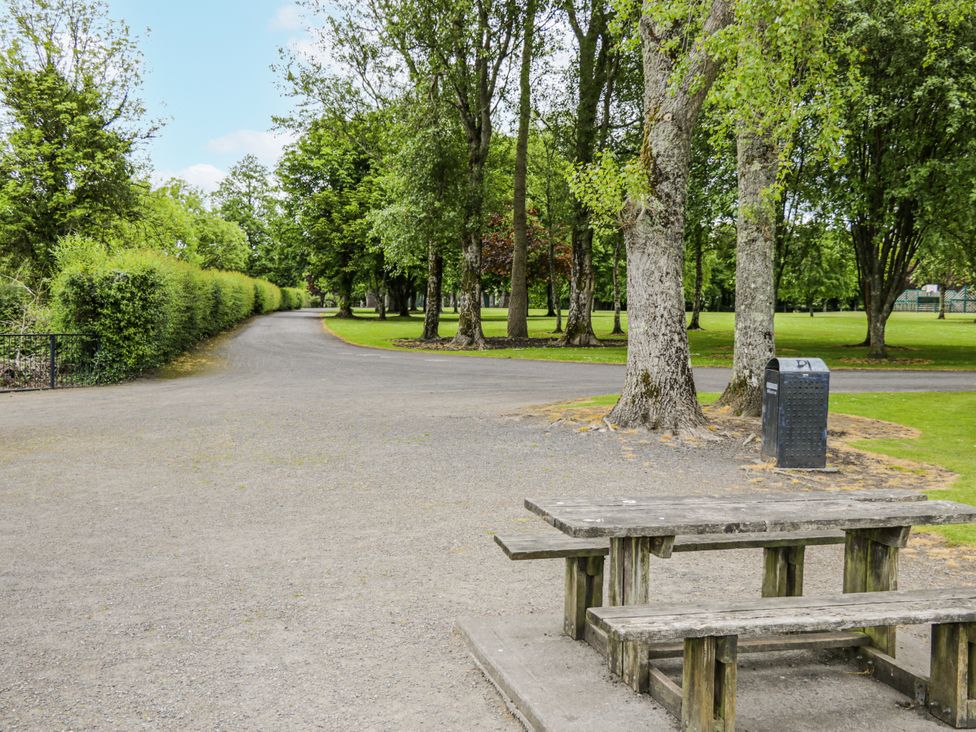 A park with a pathway, trees, and a bench at Glenview Log Cabin in Ballycastle