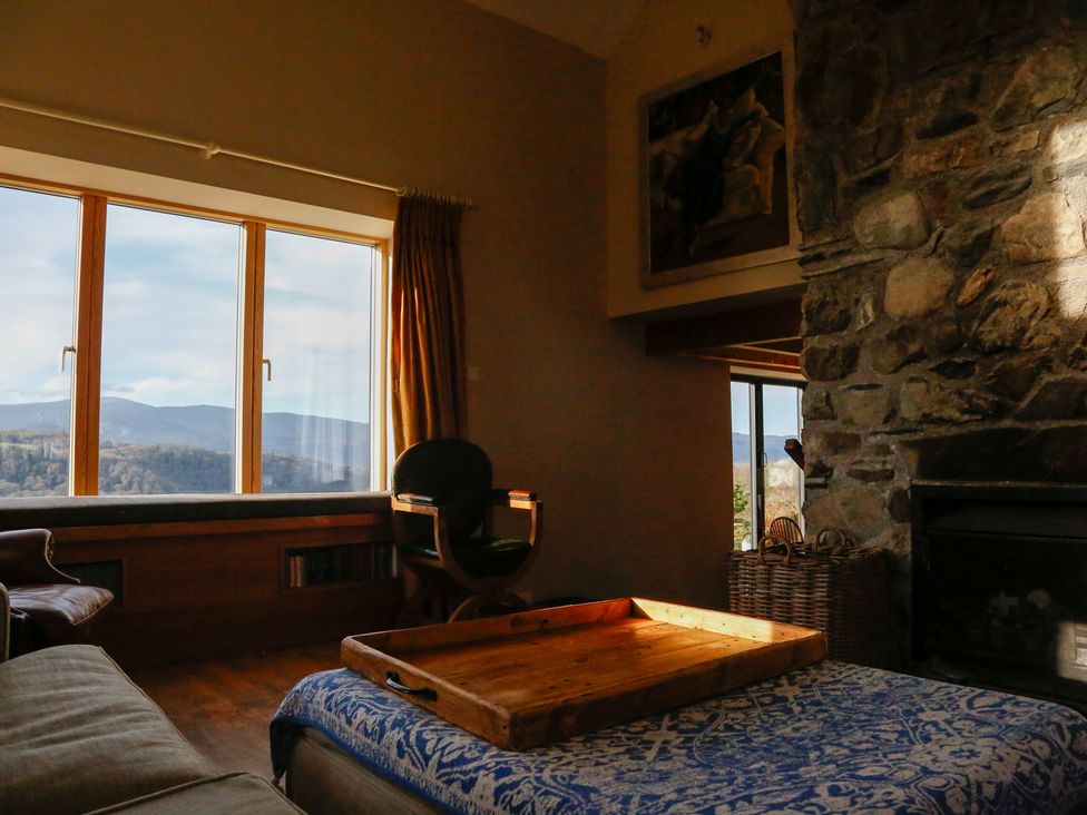 A living room with a rock wall and window view at Ty Uchaf in Colwyn Bay
