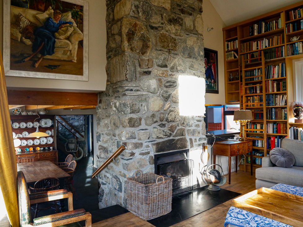 A living room with a stone fireplace and bookshelf at Ty Uchaf in Colwyn Bay