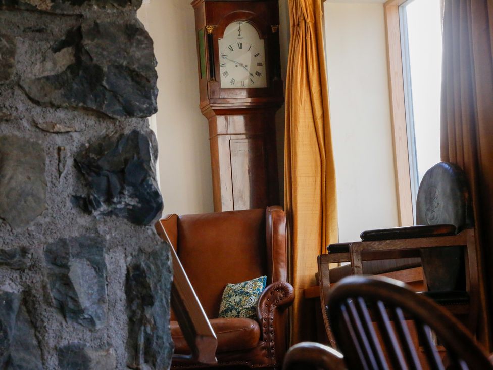 A living room with a grandfather clock and an armchair at Ty Uchaf in Colwyn Bay