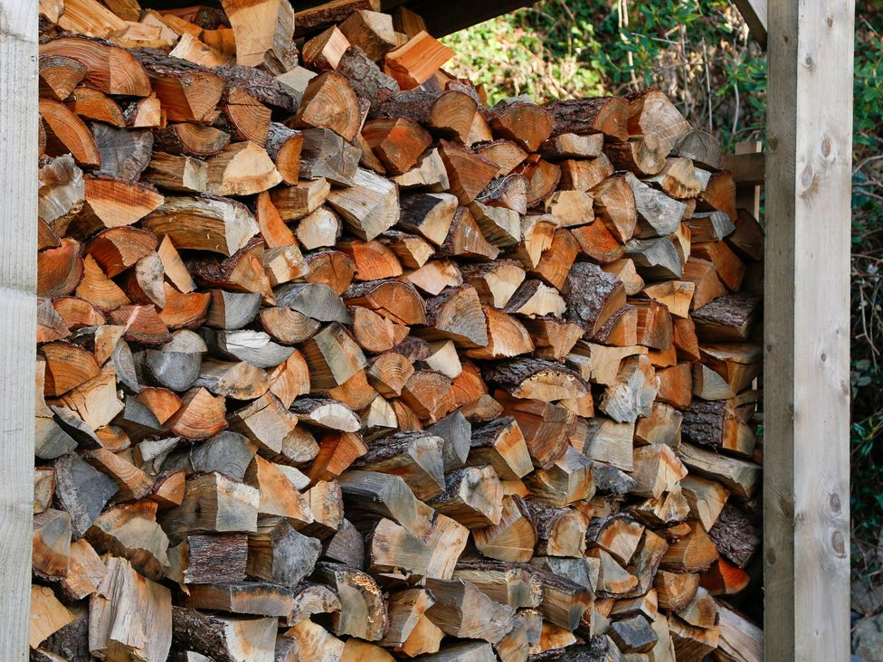 A stack of wooden logs stored in a structure at Ty Uchaf in Colwyn Bay