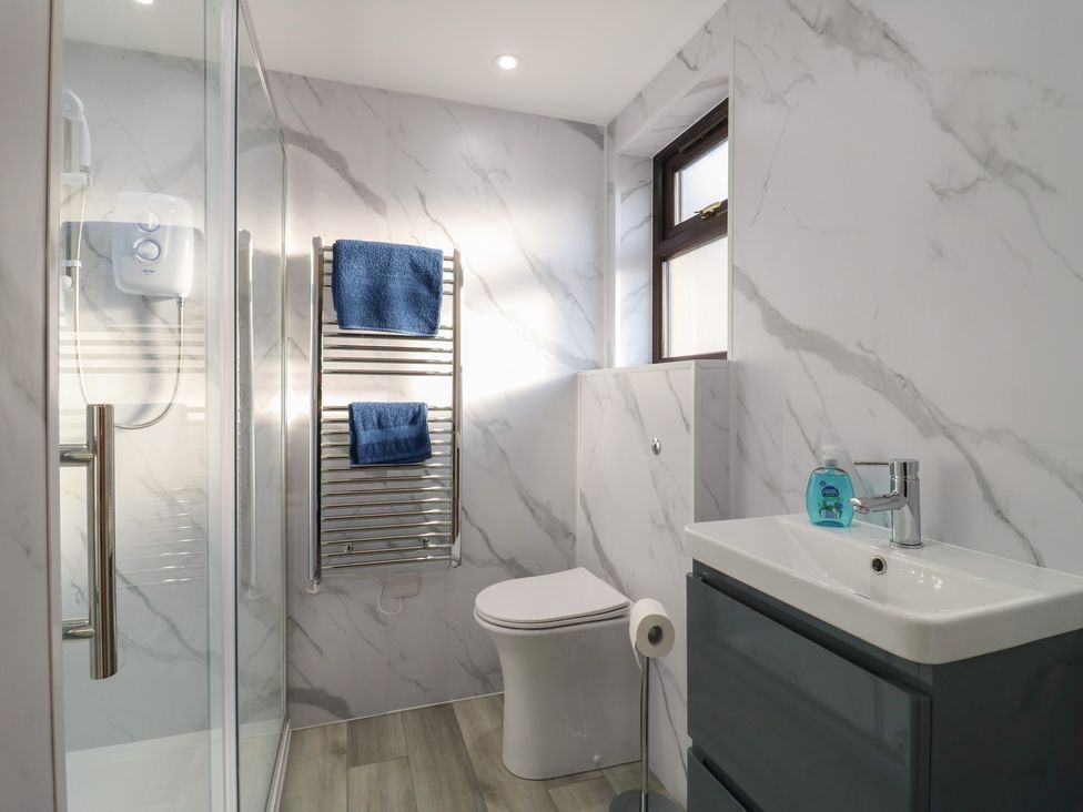 A bathroom featuring a shower, toilet, and sink at Aloe Lodge in Diss
