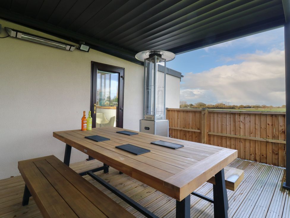 An outdoor seating area with a table and gas heater at Aloe Lodge in Diss