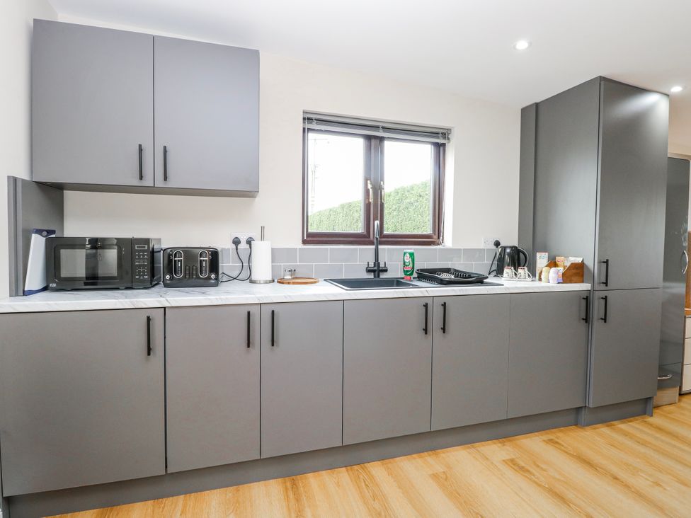 A kitchen with cabinets and appliances at Aloe Lodge in Banham
