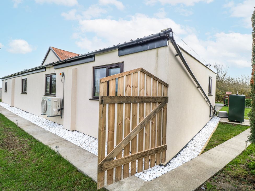 An exterior view of a house with an air conditioning unit and wooden fence at Aloe Lodge Banham