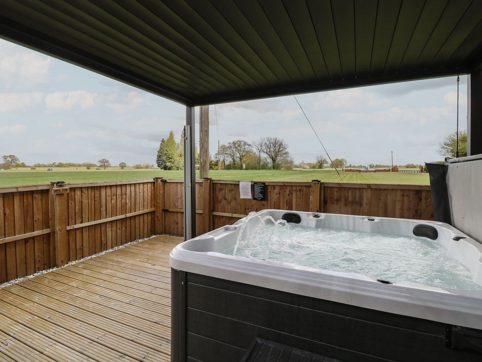 An outdoor space with a hot tub and wooden decking at Aloe Lodge in Banham
