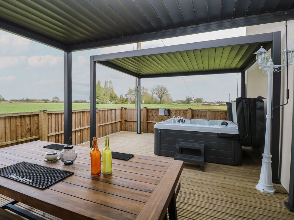 An outdoor area with a hot tub and table at Aloe Lodge in Banham