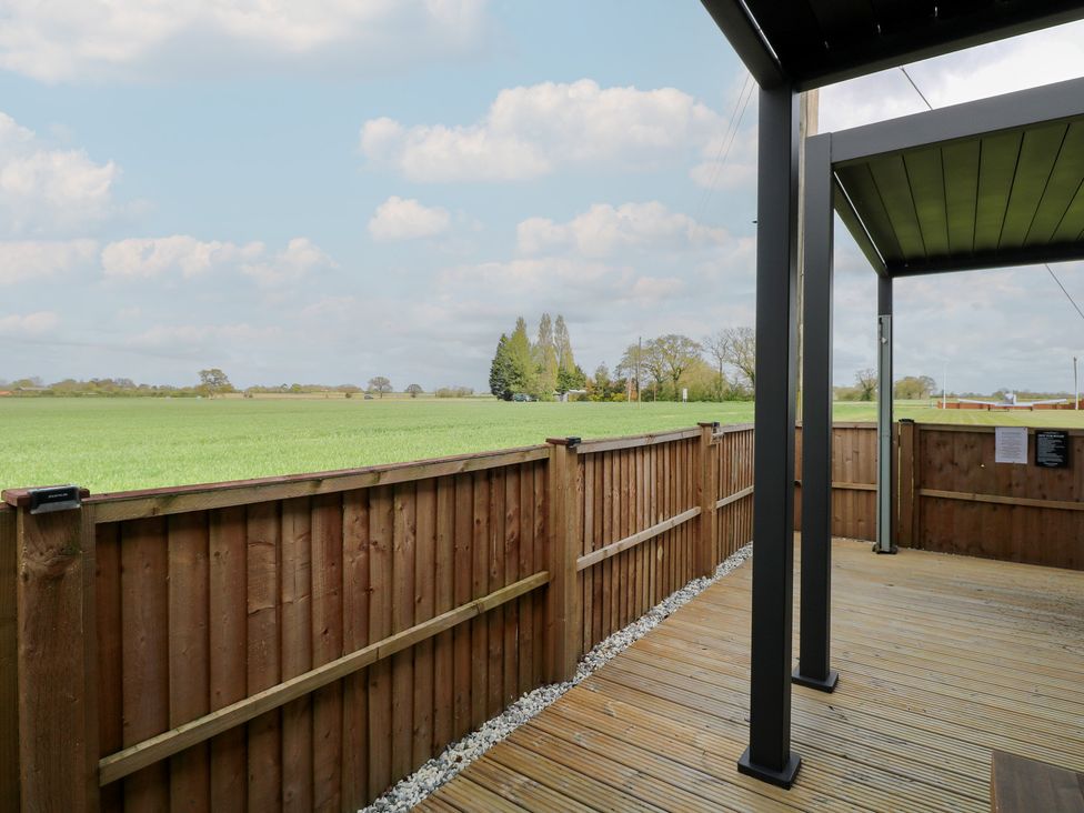An outdoor area with wooden decking and a view of grass fields at Aloe Lodge in Banham