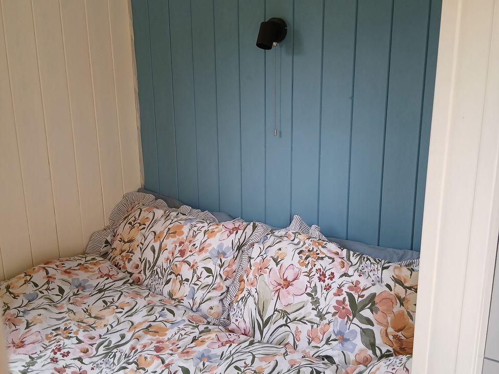 A cozy nook with floral bedding and a wall lamp at Woodie Clee Hill