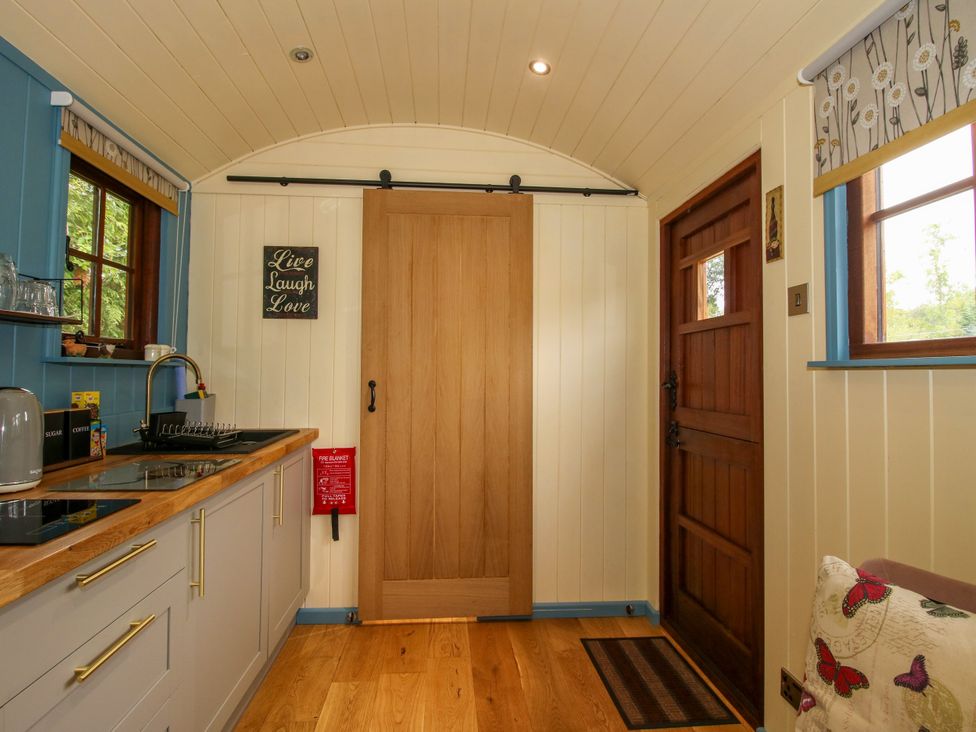 A kitchen with wooden door and window at Woodie in Clee Hill