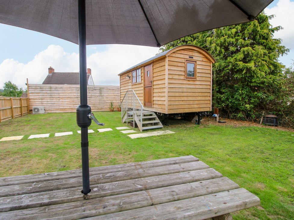 A garden with a wooden shed and a table under an umbrella at Woodie in Clee Hill