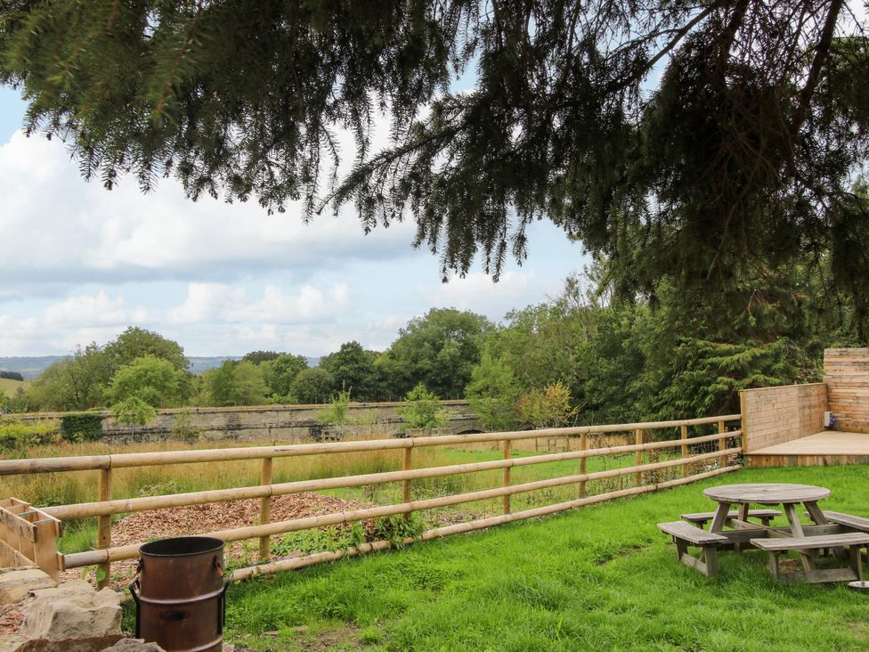 A garden with a picnic table and fire pit at Woodie in Clee Hill