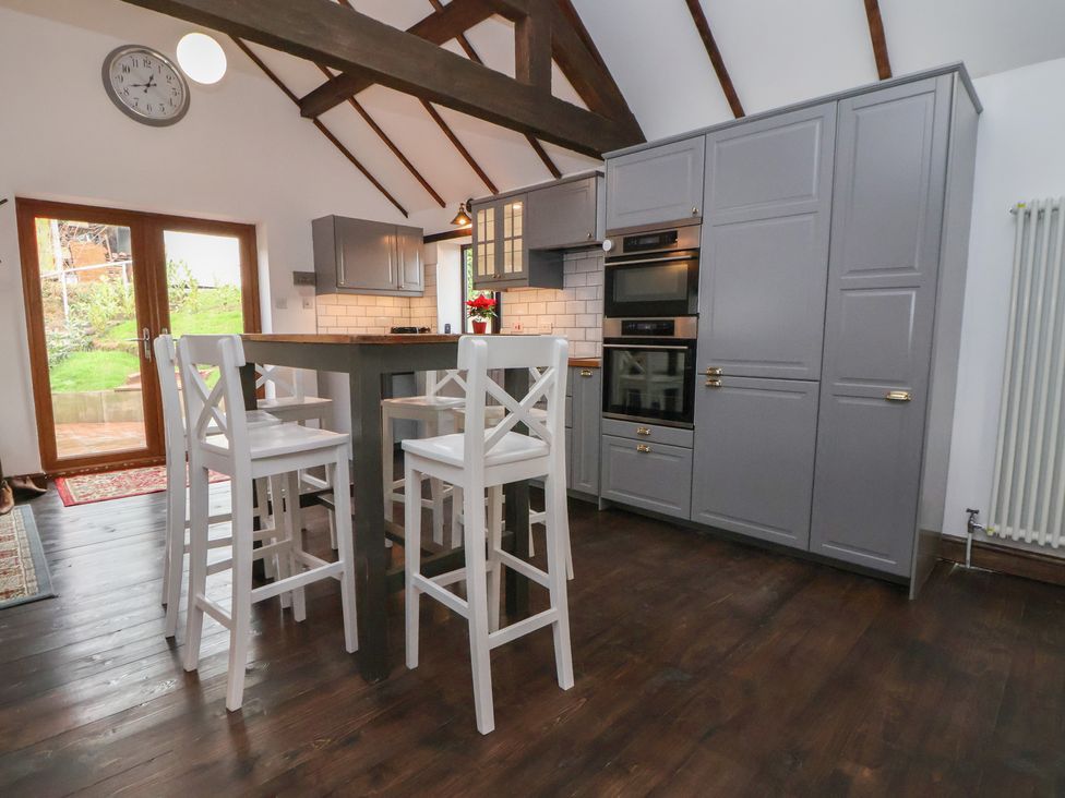 A kitchen with bar stools and cabinets at Quarry Barn in Wrexham