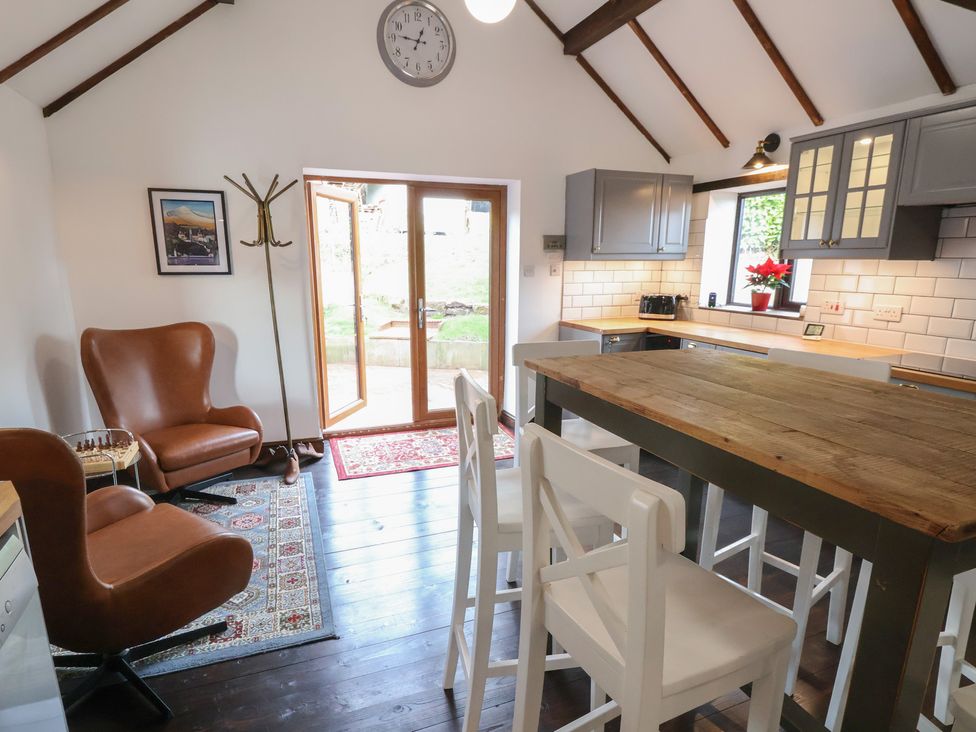 A kitchen with chairs and a wooden table at Quarry Barn in Wrexham