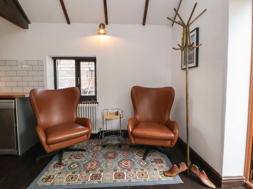 A sitting room with brown armchairs and a window at Quarry Barn Wrexham