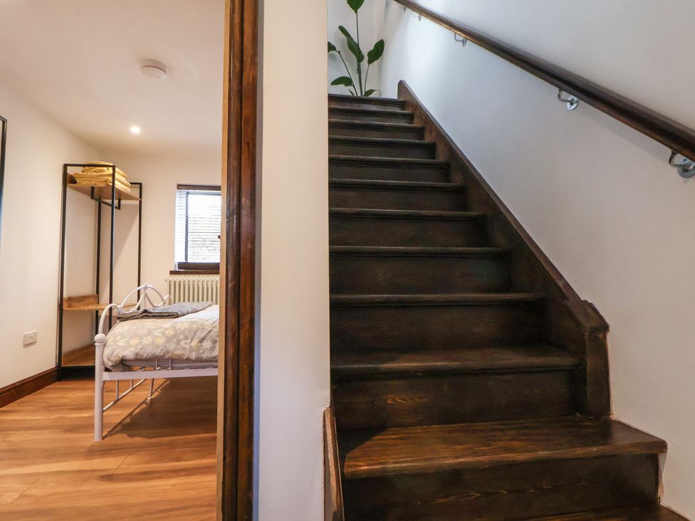 A staircase leading to a bedroom with a bed and bookshelf at Quarry Barn in Wrexham