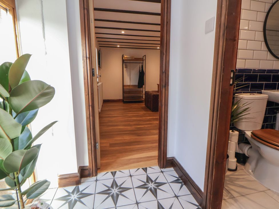 A hallway with a plant and access to a bathroom and room at Quarry Barn in Wrexham