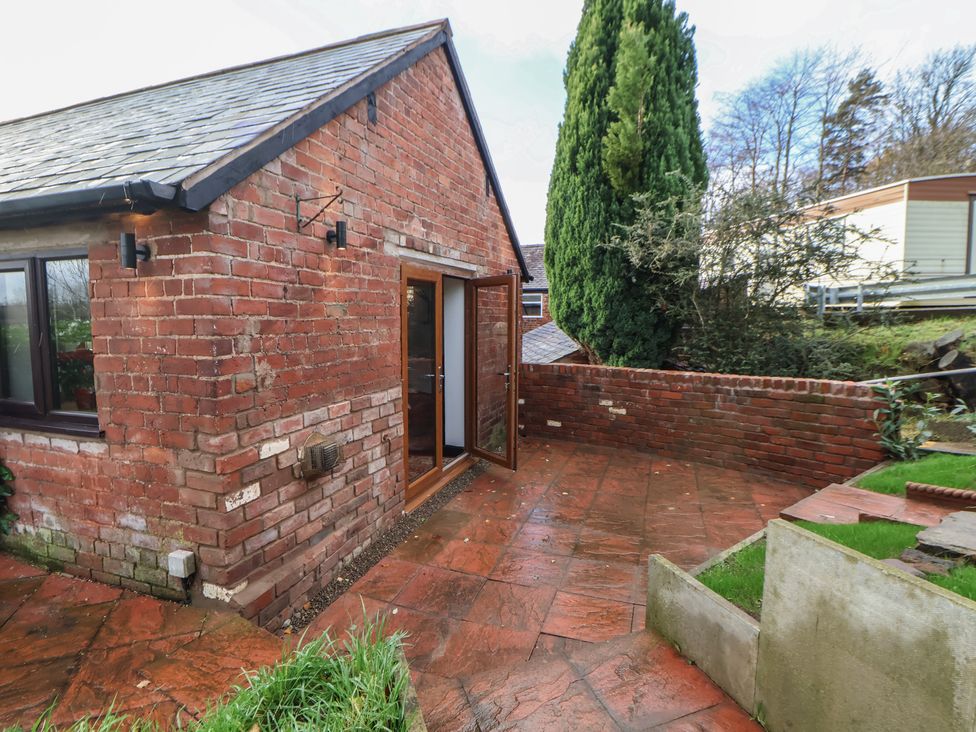 An outdoor area with a brick wall and patio at Quarry Barn Wrexham