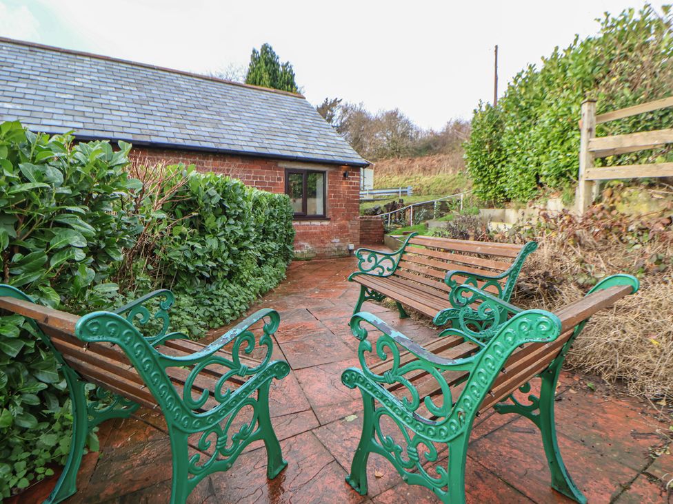 A garden with benches and hedges at Quarry Barn in Wrexham