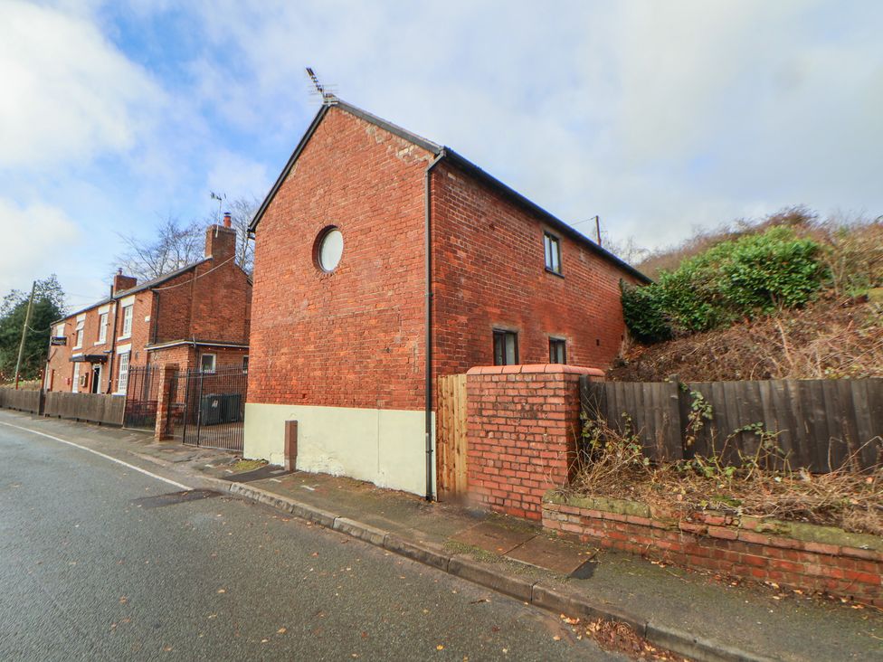 A side view of a brick house and road at Quarry Barn in Wrexham