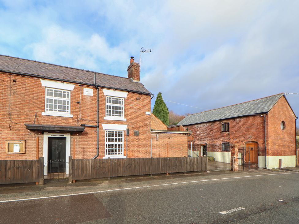 A brick house with a fence and an outbuilding at Quarry Barn in Wrexham