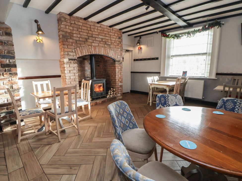A dining room with brick fireplace and wooden tables at Quarry Barn in Wrexham