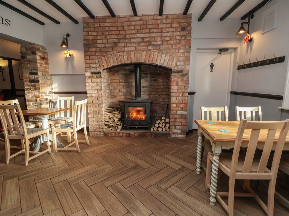 A dining room with wooden tables and a fireplace at Quarry Barn in Wrexham