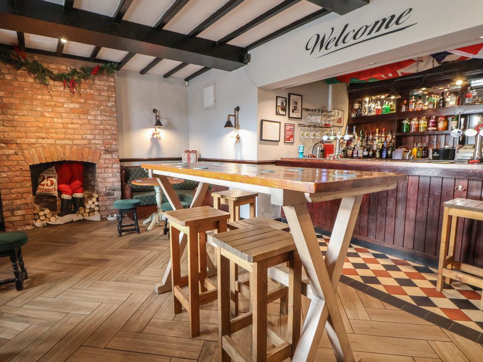 A bar area with wooden furniture and a fireplace at Quarry Barn Wrexham