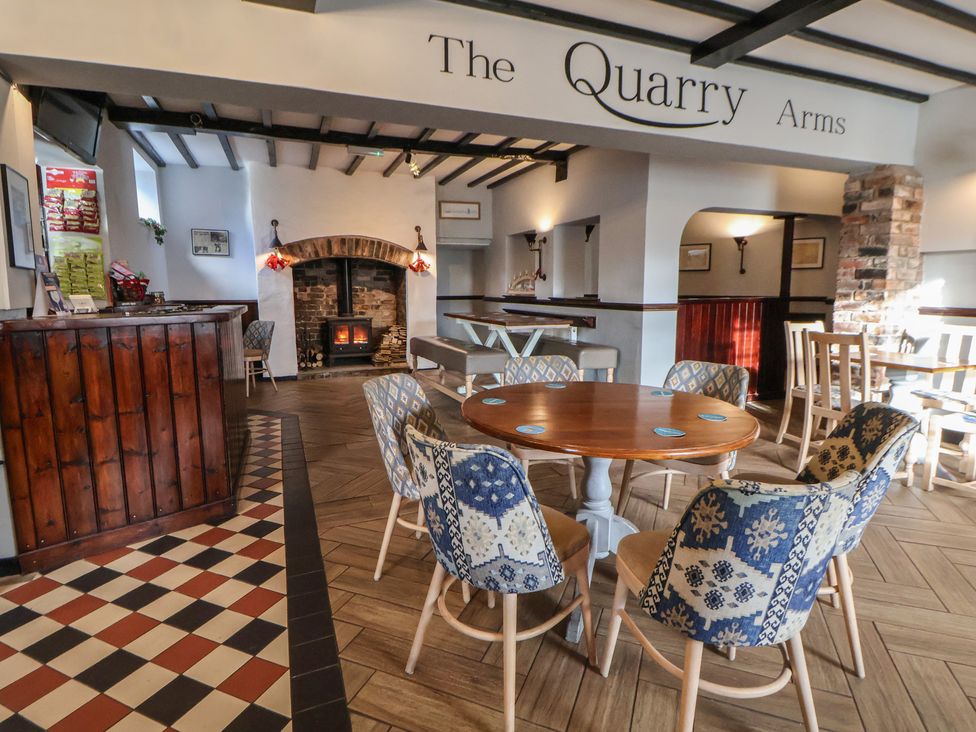A dining area with a bar counter and chairs at Quarry Barn in Wrexham