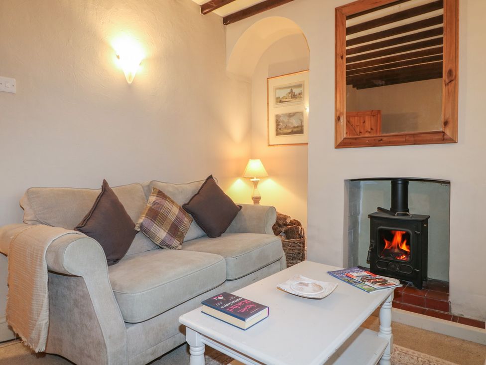 A living room with a sofa, lamp, and fireplace at Little Launde Cottage in Launde near Braunston-In-Rutland