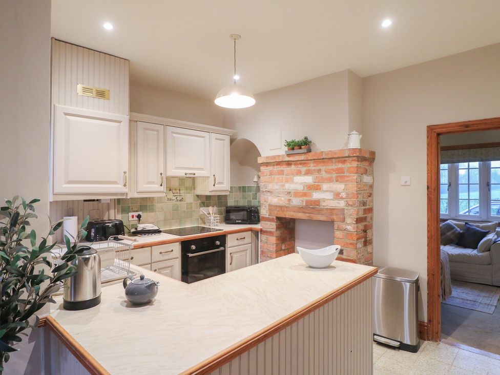 A kitchen with a brick fireplace and appliances at Little Launde Cottage in Launde near Braunston-In-Rutland