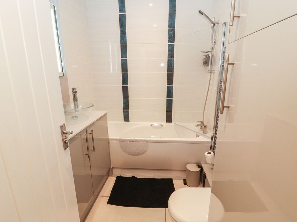 A bathroom with a bathtub, sink, and toilet at 20 Lorton Street Cockermouth