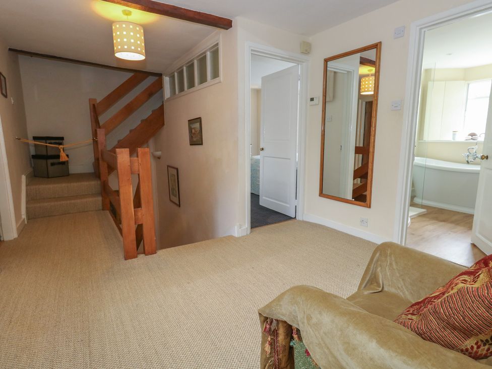 A hallway with a staircase and a mirror at Crantock