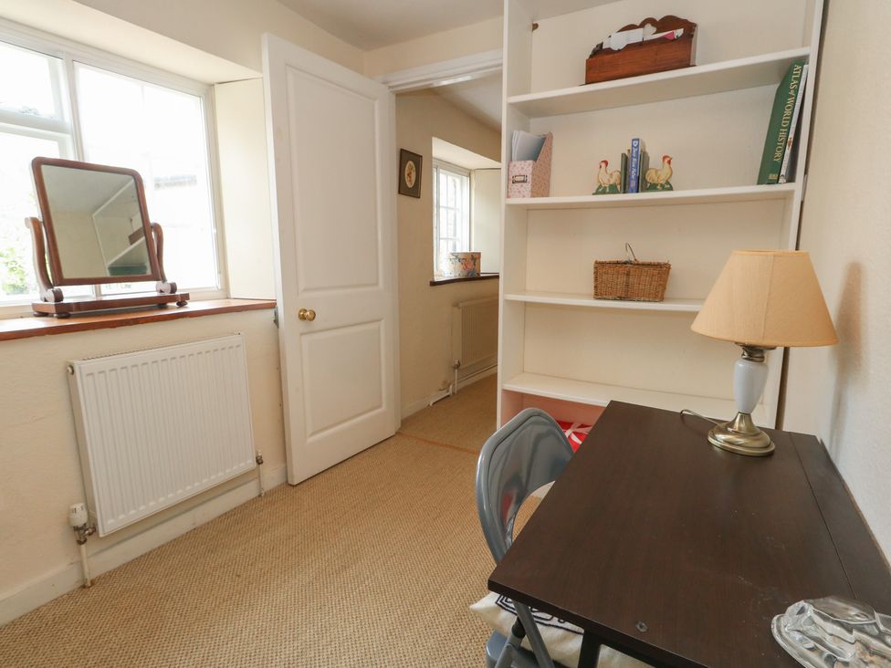 A study room with a desk, lamp, and bookshelf at Crantock