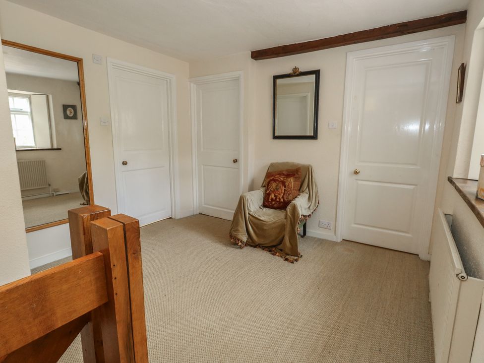 A hallway with a mirror and doorways at Crantock