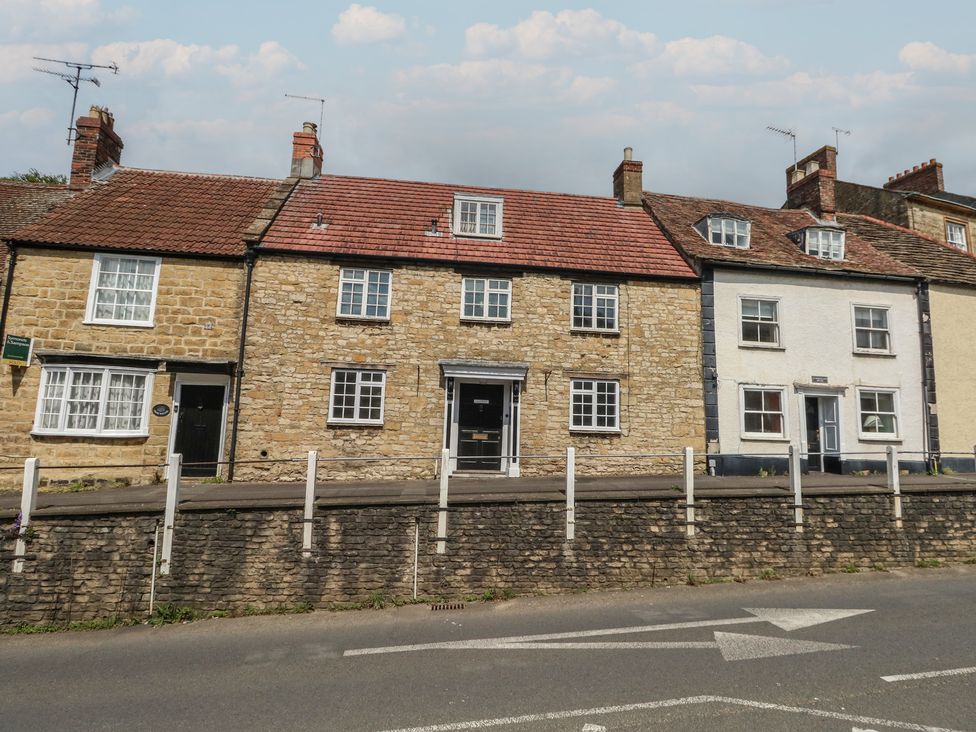A row of houses with a stone wall and street in front at Crantock