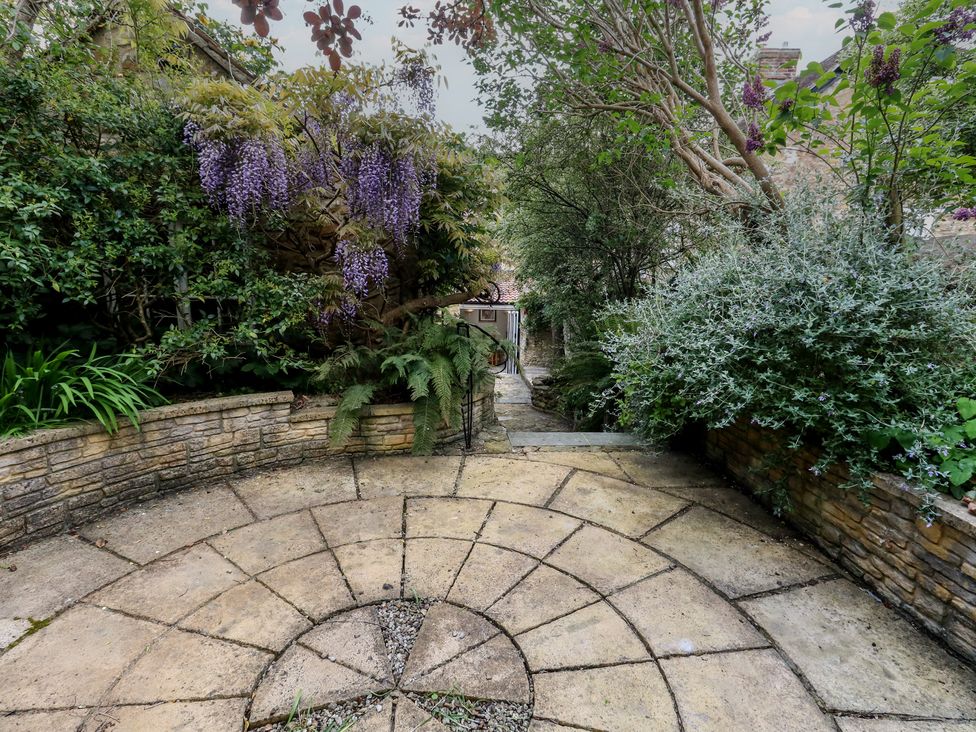 A garden with a stone pathway surrounded by plants and flowers at Crantock