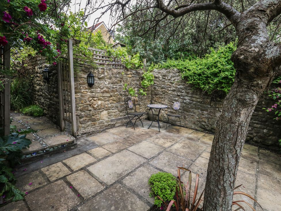 A garden with stone walls, a table and chairs at Crantock