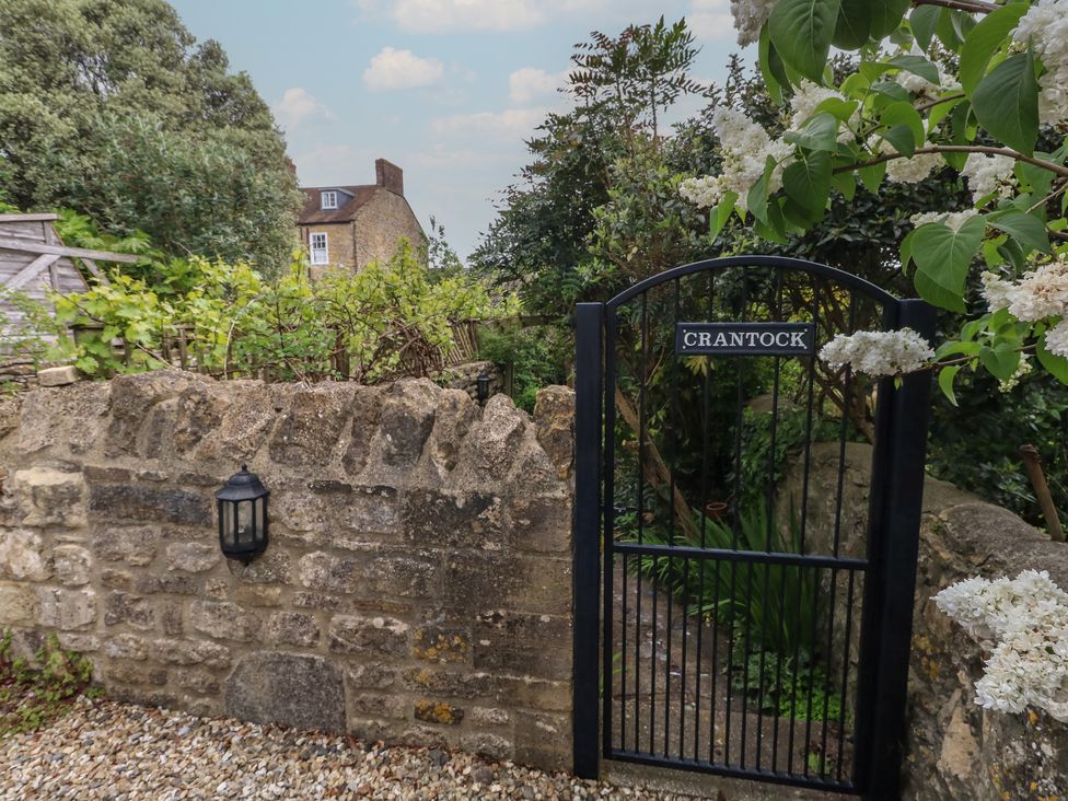 A garden gate leading to a path surrounded by plants at Crantock