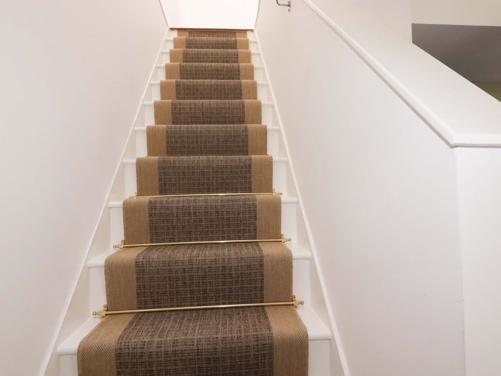 Stairs with a carpet runner and handrail at The Maisonette in Hayle