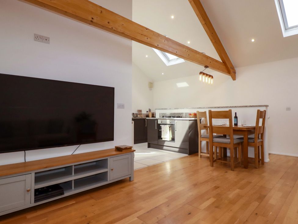A dining area with a television and kitchen at The Maisonette in Hayle