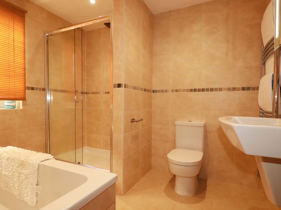 A bathroom with a shower, bathtub, toilet, and sink at The Maisonette in Hayle