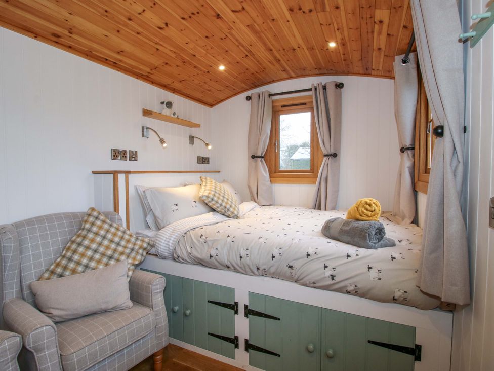 A bedroom with a bed and chair at Dave's Place Broadstone near Munslow