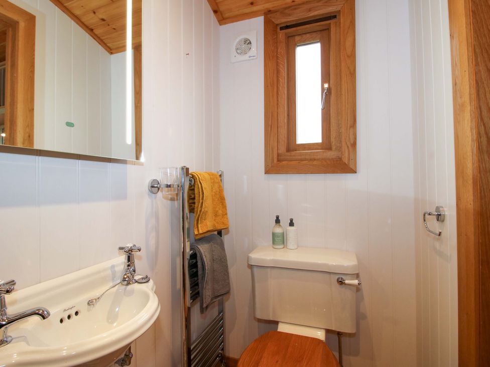 A bathroom with a sink, toilet, and window at Dave’s Place Broadstone near Munslow